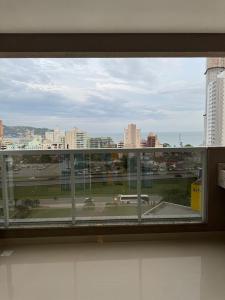 een open raam met uitzicht op de stad bij Apartamento à 390m do Mar in Itapema