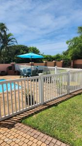 a white fence with a table and an umbrella at Aloe Self Catering in Port Shepstone