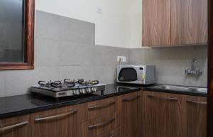 a kitchen with a stove and a microwave at PerfectStayz Shimla in Shimla