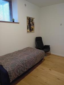 ein Schlafzimmer mit einem Bett und einem schwarzen Stuhl in der Unterkunft Olsson`s B&B in Randers