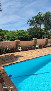 a blue swimming pool in front of a fence at Aloe Self Catering in Port Shepstone