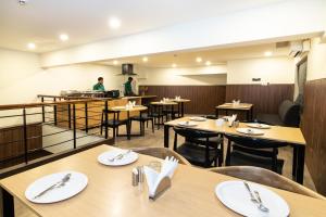 a restaurant with wooden tables and chairs and a kitchen at Sanctum Suites Richmond Road Bangalore in Bangalore