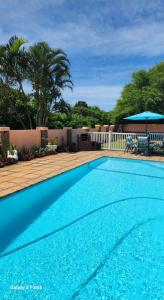 une grande piscine bleue avec une terrasse dans l'établissement Aloe Self Catering, à Port Shepstone