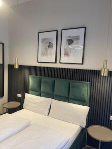 a bedroom with a bed with a green headboard and two tables at Motel Blue Messe in Berlin