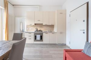 a kitchen with white cabinets and a table with chairs at Lake Sensation - Garda Lake View in Nago-Torbole