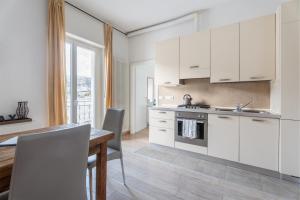 une cuisine avec des placards blancs, une table en bois et une salle à manger dans l'établissement Lake Sensation - Garda Lake View, à Nago-Torbole
