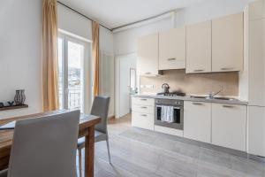 a kitchen with white cabinets and a wooden table and a dining room at Lake Sensation - Garda Lake View in Nago-Torbole