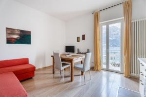 a living room with a dining room table and a red couch at Lake Sensation - Garda Lake View in Nago-Torbole