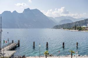 a lake with a pier and mountains in the background at Lake Sensation - Garda Lake View in Nago-Torbole