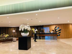 a man standing in a lobby with a vase of flowers at Shore Residences MOA Dynastel Staycation in Manila