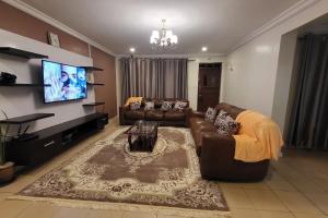 sala de estar con sofá y TV de pantalla plana en Siswi (The Nest)- The place to be., en Bungoma
