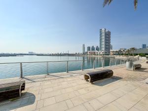 two benches sitting next to a body of water at Nasma Luxury Stays - Serenity by the Sea 1BR Apartment With Beach Views in Abu Dhabi