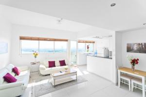 una sala de estar blanca con muebles blancos y almohadas moradas en Nasma Luxury Stays - Serenity by the Sea 1BR Apartment With Beach Views en Abu Dabi