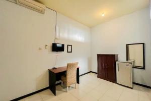 een kamer met een bureau, een tv en een koelkast bij RedDoorz Syariah near RSUD Tuban in Tuban