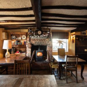 a dining room with a fireplace and a table and chairs at The Pheasant Pub at Gestingthorpe Stylish Boutique Rooms in The Coach House in Gestingthorpe