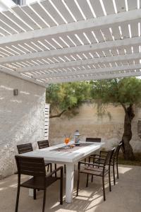 Lido degli Angeli Case Vacanza-Beach في بونتا بروسسيوتو: طاوله بيضاء وكراسي تحت بروغولا بيضاء