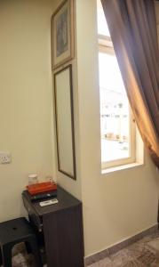 Zimmer mit einem Schreibtisch, einem Spiegel und einem Fenster in der Unterkunft Sweet Inn Guest House in Kuantan