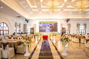 - une salle de banquet avec des tables blanches, des chaises et des fleurs dans l'établissement Hoa Nam Hotel, 