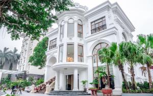 a white building with palm trees in front of it at Hòa Nam Hotel in Nam Dương