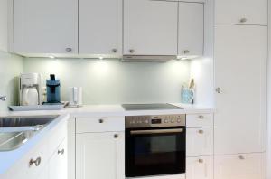 uma cozinha com armários brancos e um forno preto em Achter Duenem App 1 em Wenningstedt
