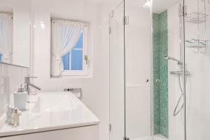 uma casa de banho branca com um lavatório e um chuveiro em Achter Duenem App 1 em Wenningstedt