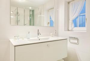 uma casa de banho branca com um lavatório e um espelho em Achter Duenem App 1 em Wenningstedt