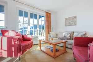uma sala de estar com duas cadeiras vermelhas e uma mesa em Fewo Christopher App 5 em Wenningstedt