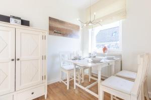 uma sala de jantar branca com uma mesa e cadeiras brancas em Haus Sonnenschein Whg G em Wenningstedt