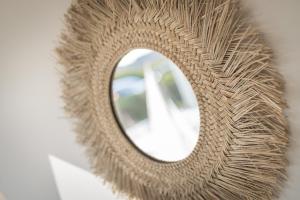 a mirror with a wicker frame on a wall at Engelskoje in Wenningstedt