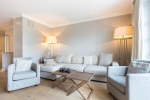 ein Wohnzimmer mit einer Couch und zwei Stühlen und einem Tisch in der Unterkunft Düün Hüs, App. 2 in Westerland