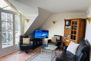 uma sala de estar com cadeiras de couro preto e uma televisão de ecrã plano em Landhaus Normannenweg App 4D em Wenningstedt