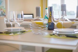 ヴェスターラントにあるNette Sun App 10のグラスと皿、ワインのボトルを用意したテーブル