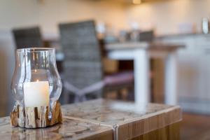 świeca w szklanej wazie siedzącej na stole w obiekcie Wendinghues App 7 w mieście Wenningstedt