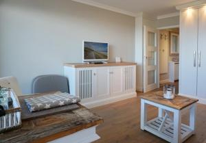 a living room with a table and a television at Seafront Duenenhof zum Kronprinzen in Wenningstedt