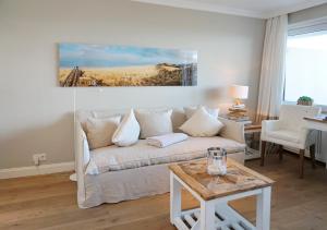 uma sala de estar com um sofá branco e uma mesa em Seafront Duenenhof zum Kronprinzen em Wenningstedt