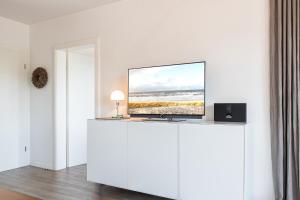 ヴェニングシュテットにあるSchloss am Meer App 27の白いキャビネットの上に座る薄型テレビ
