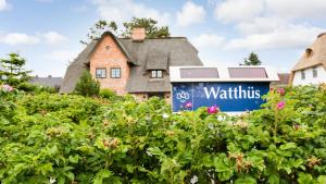 een huis met een bord voor een struik bij Watthues Wenningstedt in Wenningstedt