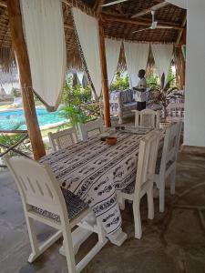 una mesa y sillas con una mesa y una mujer en el fondo en Cosy Cottage Marine Park at Malindi beach en Malindi