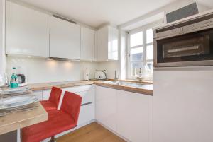 ヴェニングシュテットにあるLandhaus Wiesenwegの白いキャビネットと赤い椅子付きの白いキッチン