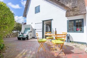a patio with a table and chairs in front of a house at Kampende II in Tinnum