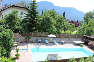 einen Pool in einem Garten mit Stühlen und einem Sonnenschirm in der Unterkunft Gasthof Anny in Marling