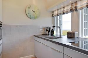 a kitchen with a clock on the wall and a sink at Seeblick in Wenningstedt