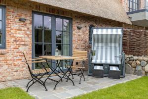 a patio with a table and chairs next to a building at Fien to Huus in Wenningstedt