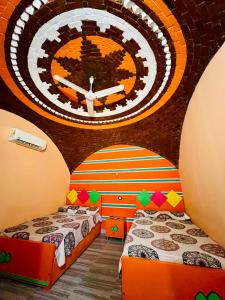 two beds in a room with a clock on the wall at Fadlos Anay Nubian Guesthouse فضلوس أناي in Aswan