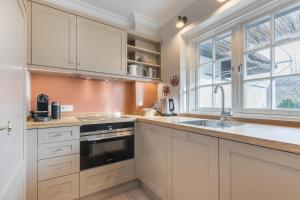 eine Küche mit weißen Schränken, einem Waschbecken und einem Fenster in der Unterkunft Haus Pidder Lyng, Schilfblatt, Wohnung 2 in Keitum