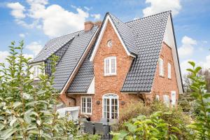 ein rotes Backsteinhaus mit einem schwarzen Dach in der Unterkunft Haus Seaside in Wenningstedt-Braderup
