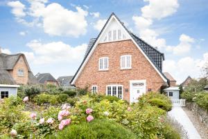 ein Backsteinhaus mit einer weißen Tür und Blumen in der Unterkunft Haus Seaside in Wenningstedt-Braderup