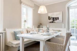 ein weißes Esszimmer mit einem weißen Tisch und Stühlen in der Unterkunft Haus Seaside in Wenningstedt-Braderup