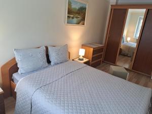 ein Schlafzimmer mit einem Bett mit einer weißen Bettdecke und einem Spiegel in der Unterkunft Sweet home in Šiauliai
