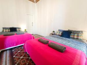 By Urquinaona Rooms في برشلونة: سريرين في غرفة ذات أغطية حمراء